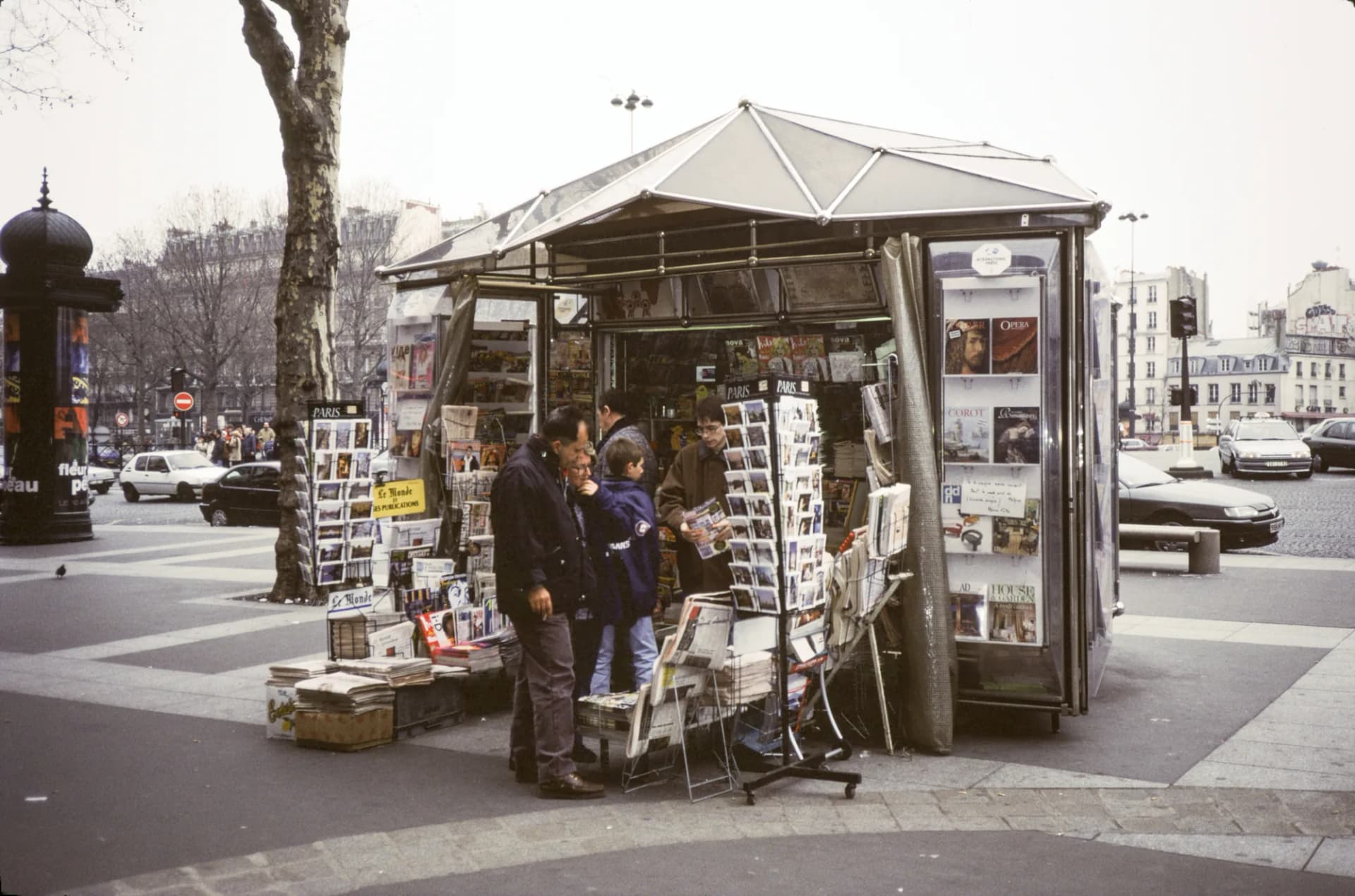Un kiosque à journaux parisien, ses présentoirs couverts de quotidiens et de magazines